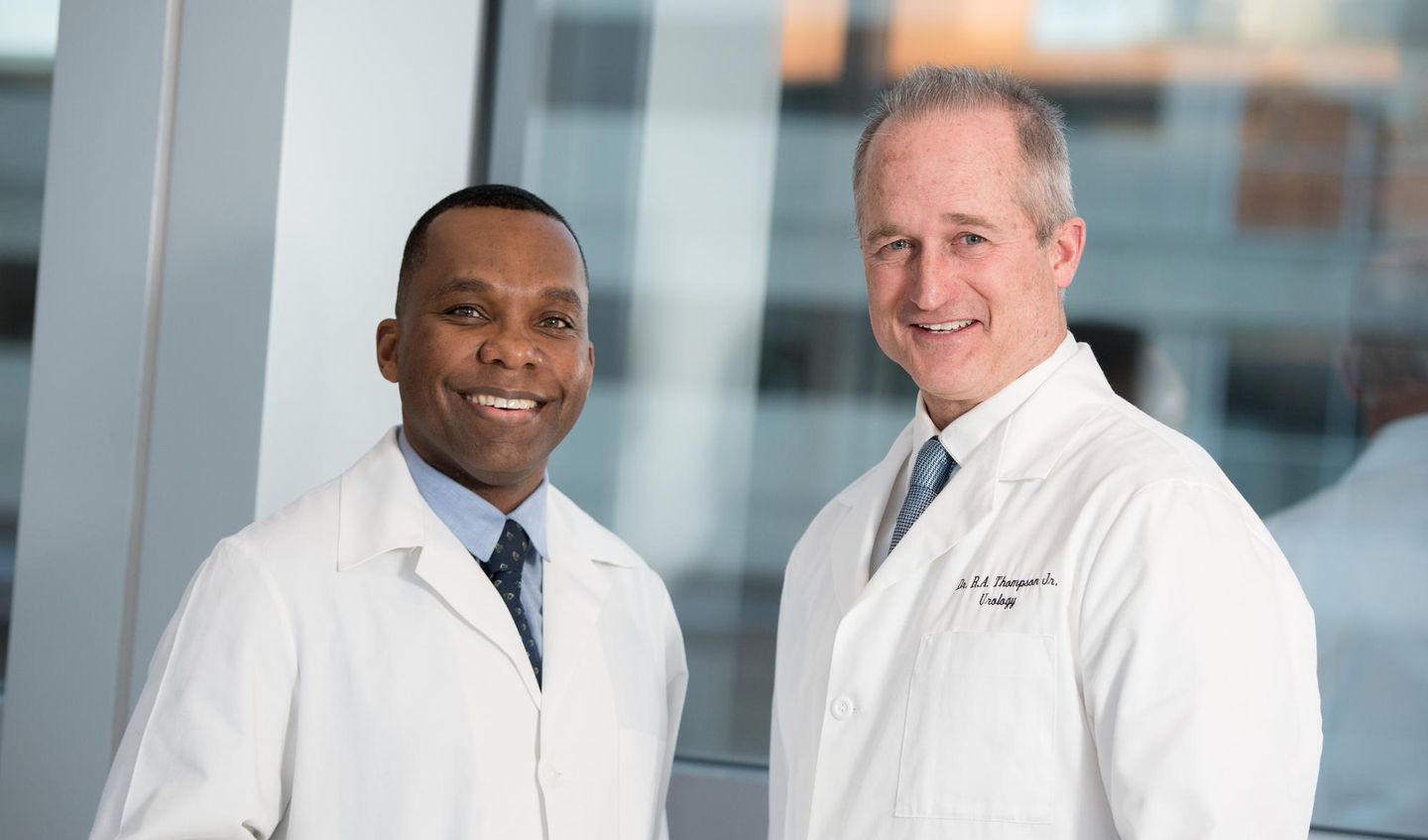 Two physicians in white lab coats smiling in a modern clinical setting